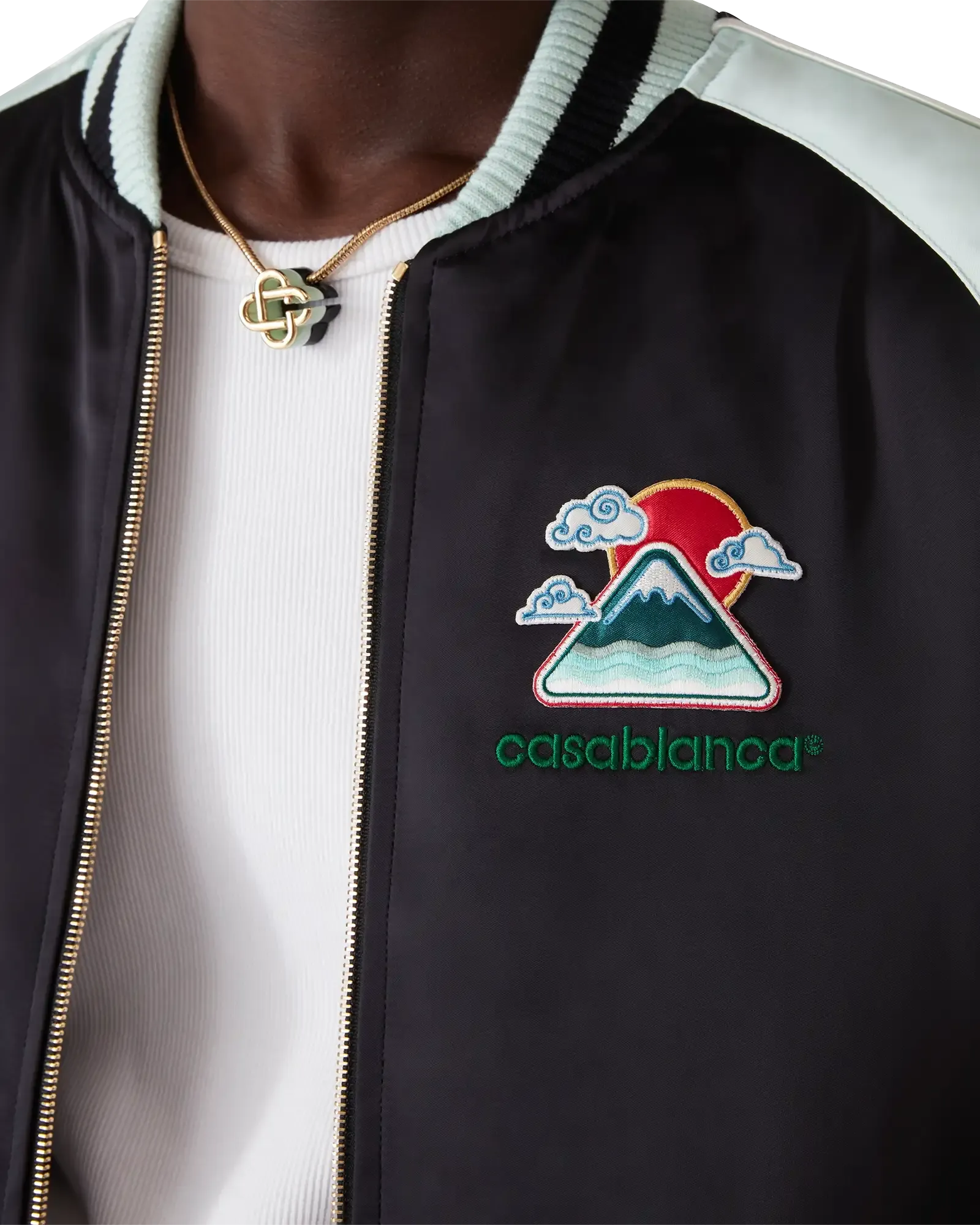 Close-up of raglan sleeve with green and black panels and piping on Casablanca Embroidered Satin Bomber Jacket